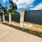 Corrugated iron fence with sandstone pillars