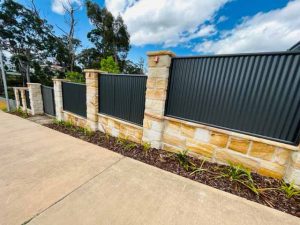 Corrugated iron fence with sandstone pillars