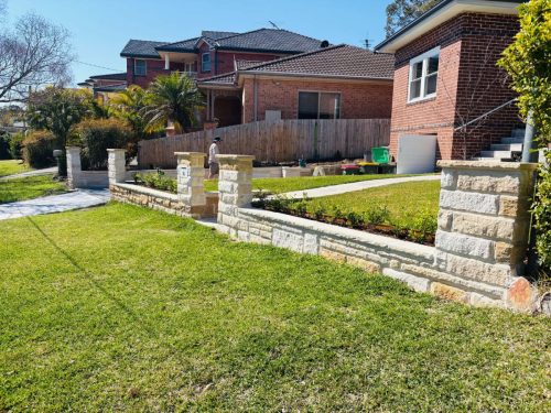 sandstone brick front fence with piers and hedging